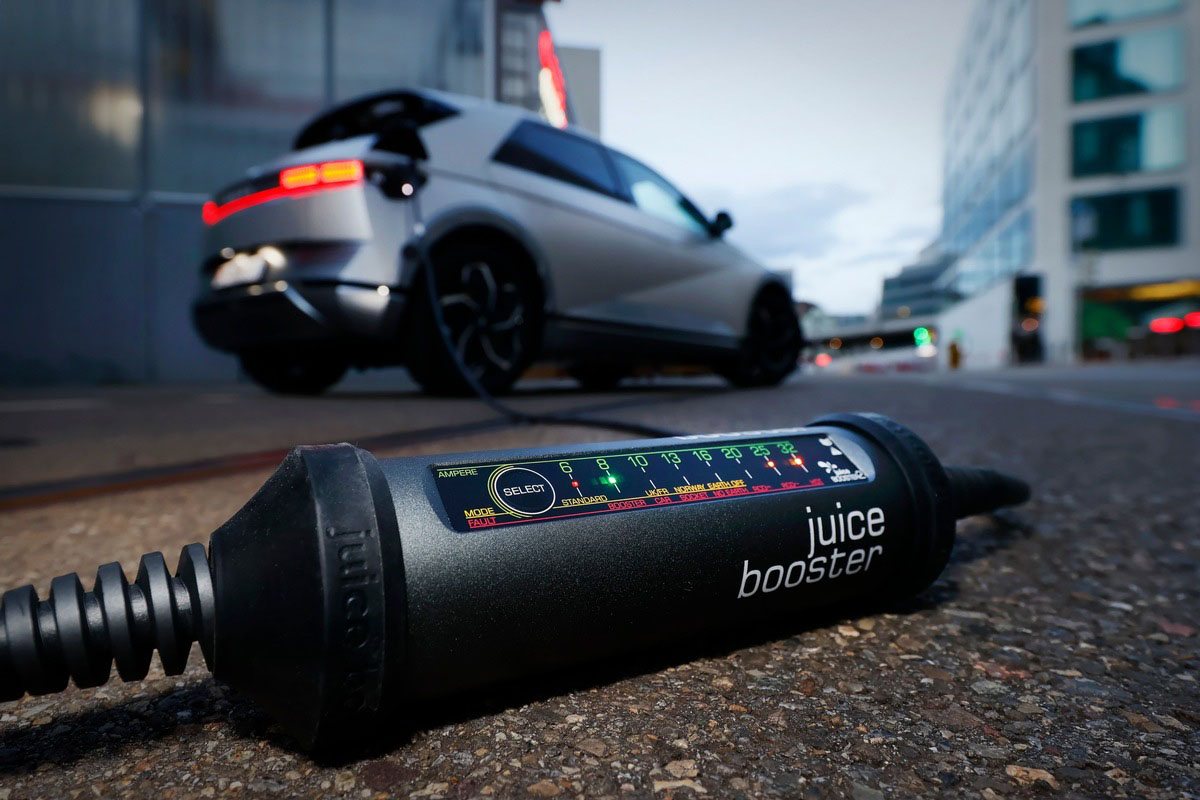 Câble de recharge connecté Juice Booster avec véhicule électrique en arrière-plan
