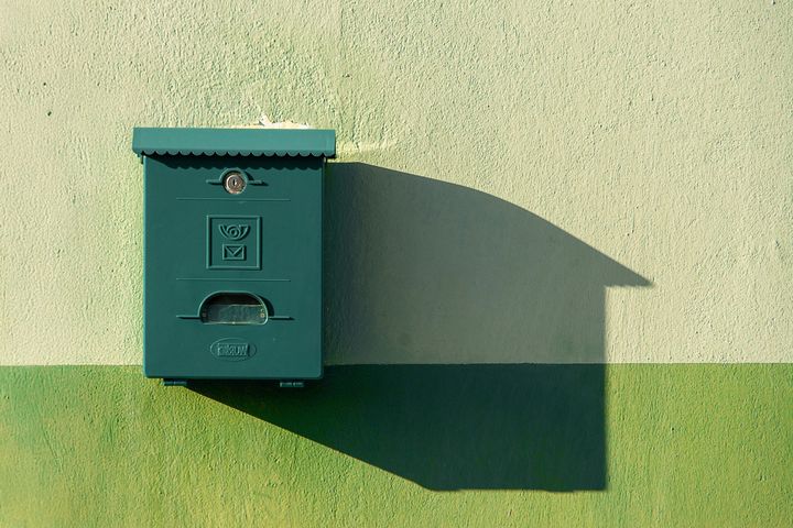 Gruener Briefkasten an einer Hauswand