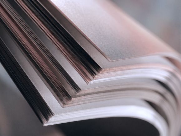 Aufgefaecherter Papierstapel, die Blattkanten leuchten im Gegenlicht