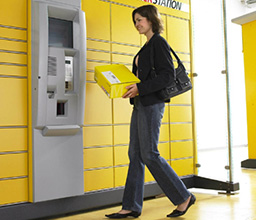 Woman with parcel in front of a parcel system