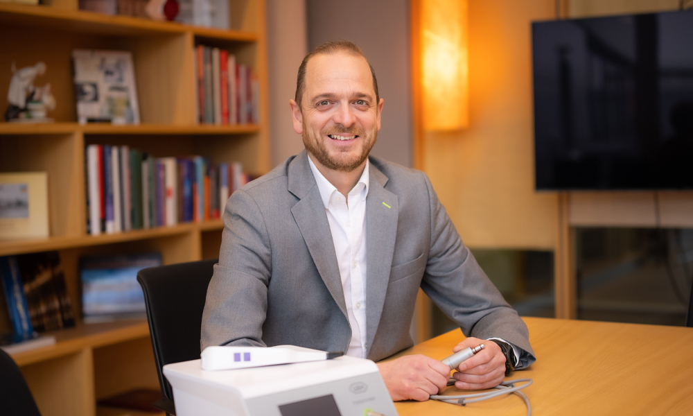 Andreas Brandstätter smiles at the camera while holding the motor of an Implantmed device. Andreas Brandstätter smiles at the camera while holding the motor of an Implantmed device.