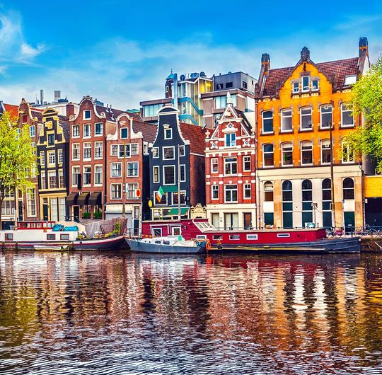 Colorful buildings along a canal with boats parked in front of them on a sunny day
