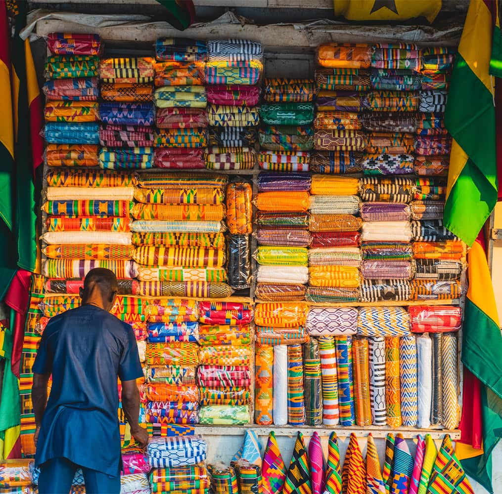 A man facing away from the camera and looking at a wall with many various fabrics in many different designs