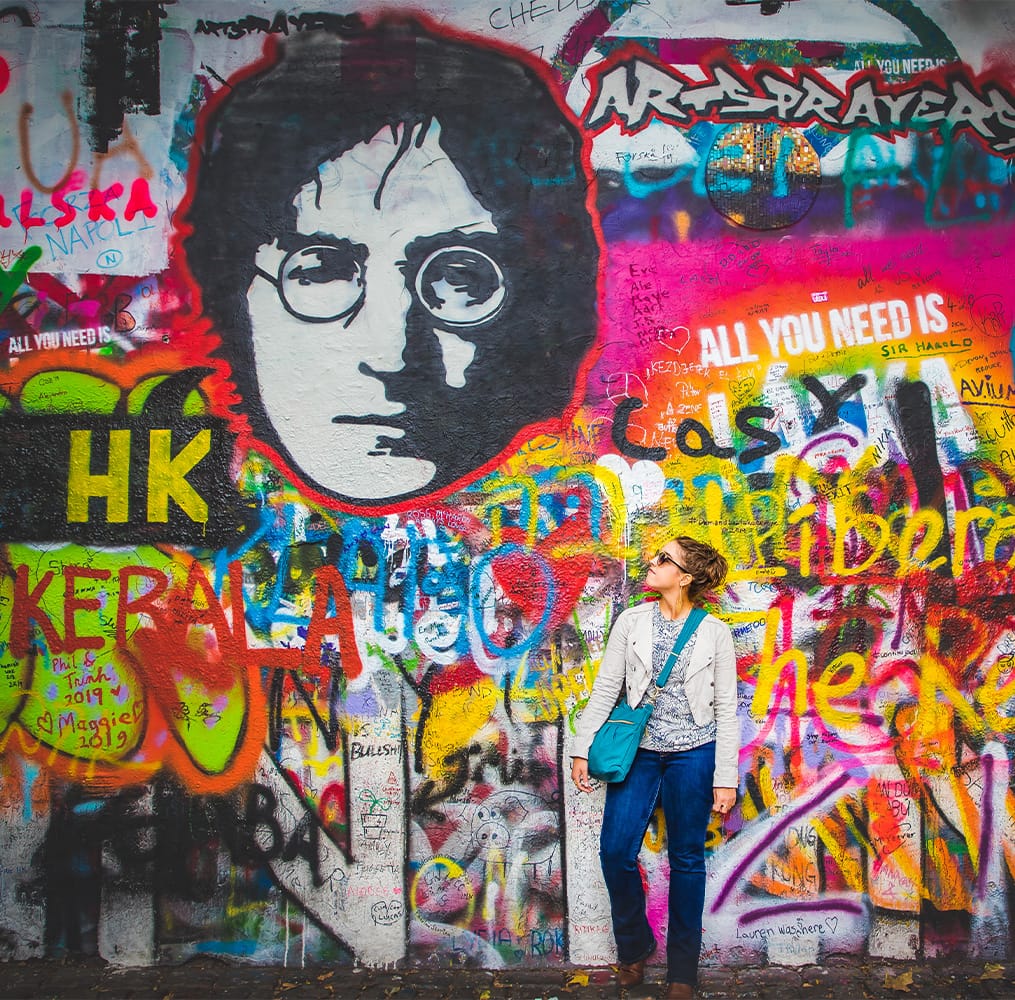 A young woman standing in front of a wall covered in graffiti