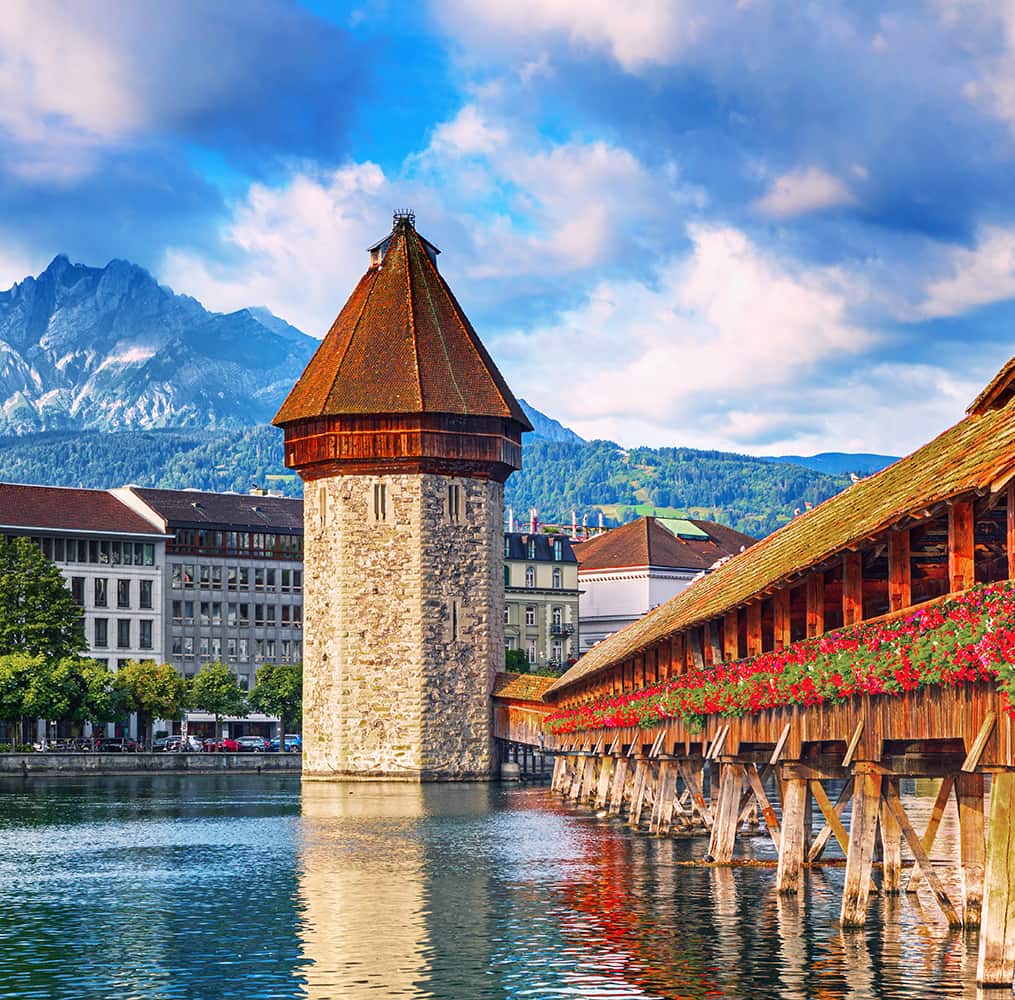 A medieval stone tower and wooden bridge spanning a river