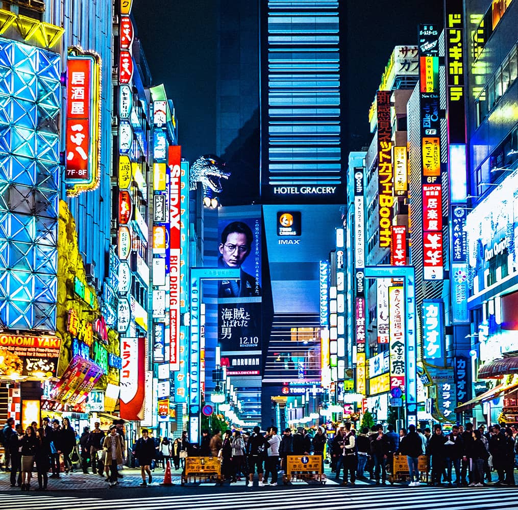 A busy city street lined with digital billboards at night
