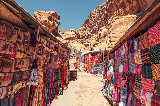 An outdoor market in the desert with vibrant colored textiles for sale