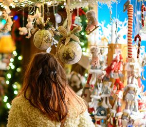 A woman walking past market stalls with Christmas ornaments at night