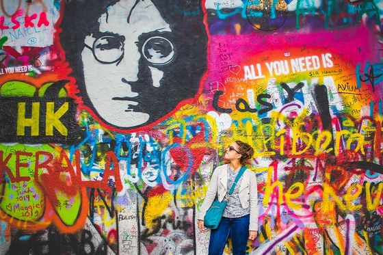 A young woman standing in front of a wall covered in graffiti