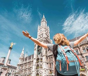 A person holding their hands up in the air and looking at a grand building