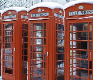 A row of red telephone booths topped with snow