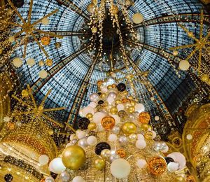 Inside of a domed ceiling decorated with yellow lights and white and gold balloons