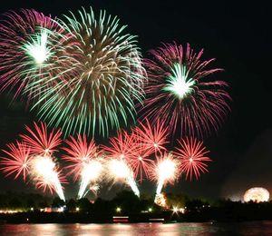 View of a city across a body of water with fireworks exploding above it