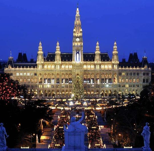 Aerial view of a city square decorated with lights and a large ornate building at night