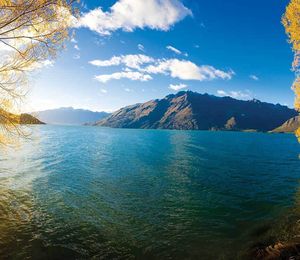 A blue body of water on a sunny day with mountains in the distance