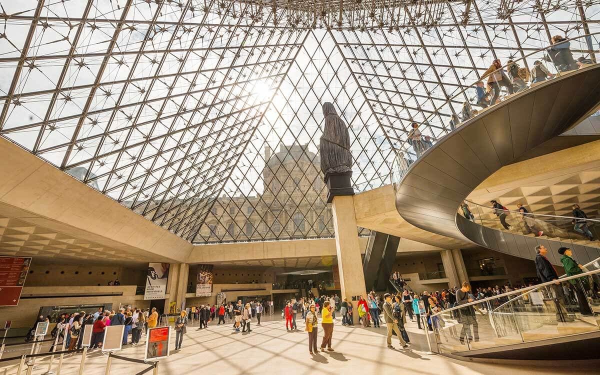 People standing in the main lobby of the Louvre Museum in France.