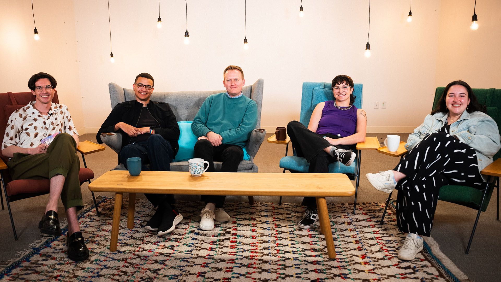 Five people sitting in chairs smiling.