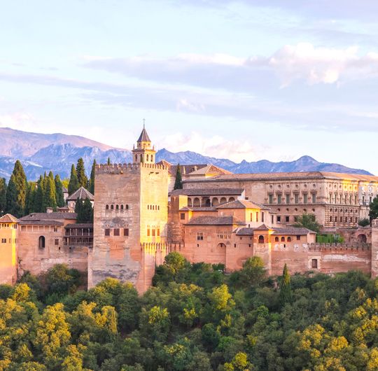 A large stone fortress with snow-capped mountains in the background