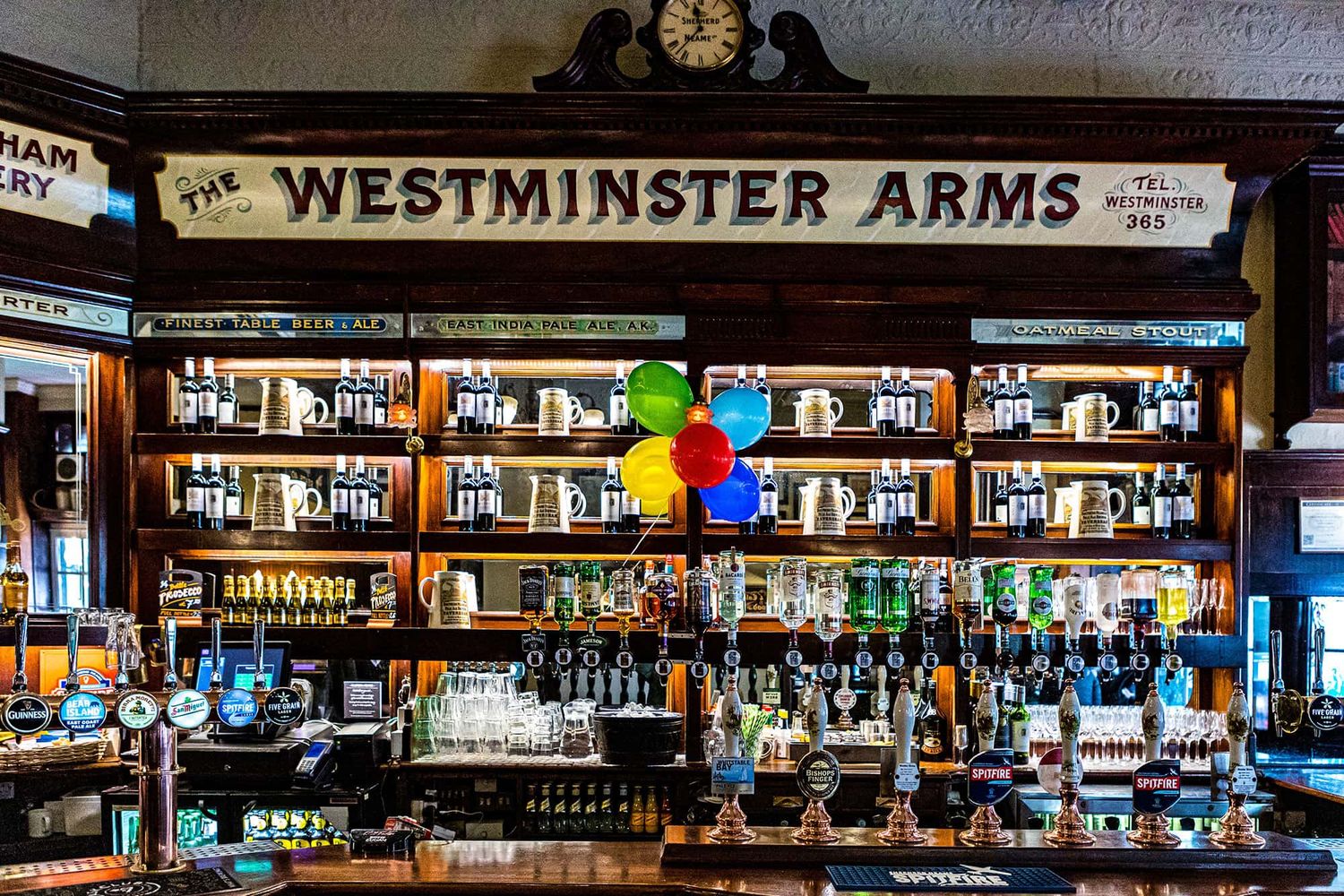 A lit up liquor shelf in an English bar.