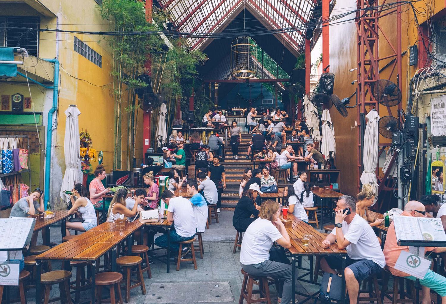 An outdoor restaurant in Thailand with people enjoying beers and food.