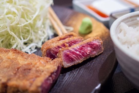 A plate of meat and a bowl of rice on a table