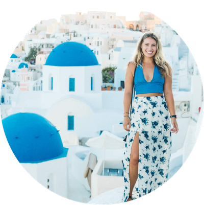 A woman posing in front of white buildings with blue domes on top