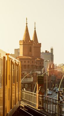 An orange train on traintracks with a grand ornate building in the background with multiple pointed domes