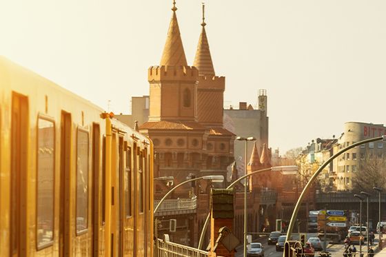 An orange train on traintracks with a grand ornate building in the background with multiple pointed domes