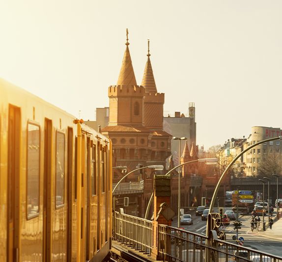 An orange train on traintracks with a grand ornate building in the background with multiple pointed domes
