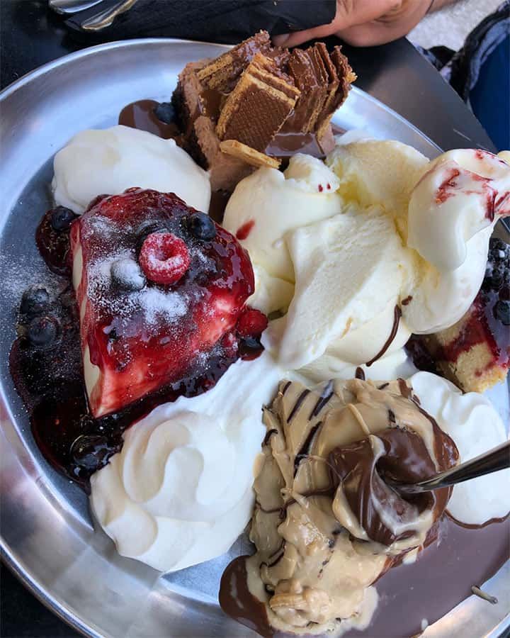 A plate of Greek dessert including ice cream, cookies, and assorted cakes.