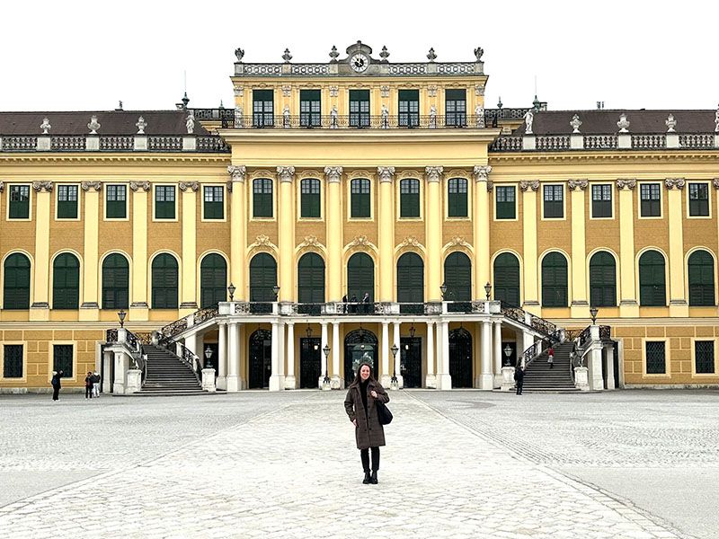 A woman standing in front of a big yellow castle.