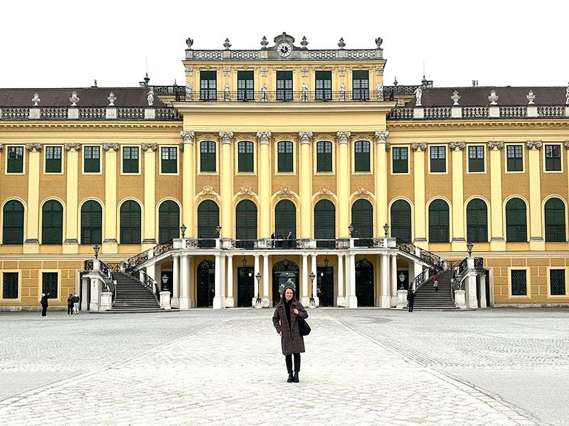 A woman standing in front of a big yellow castle. 