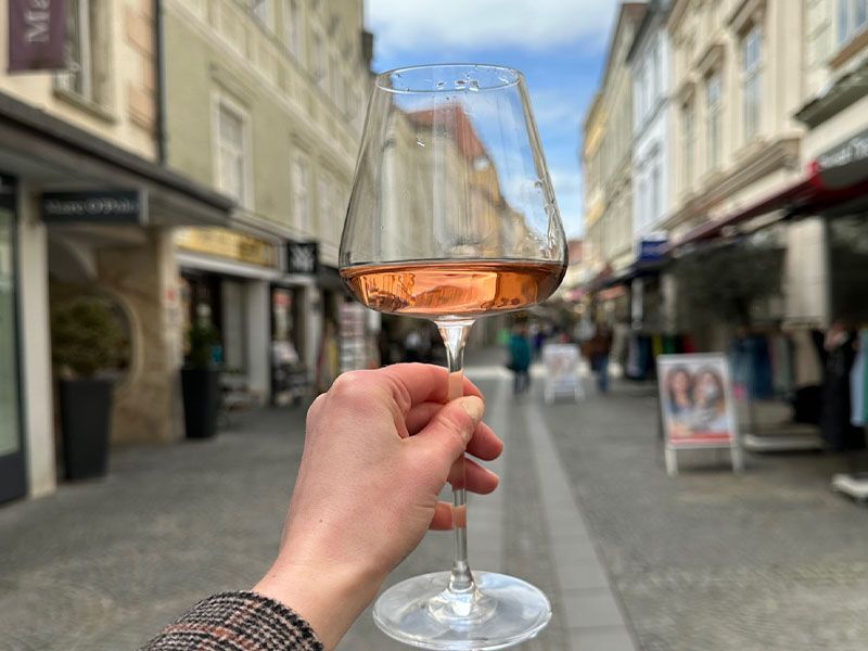 A handle holding up a glass of wine in front of a street.