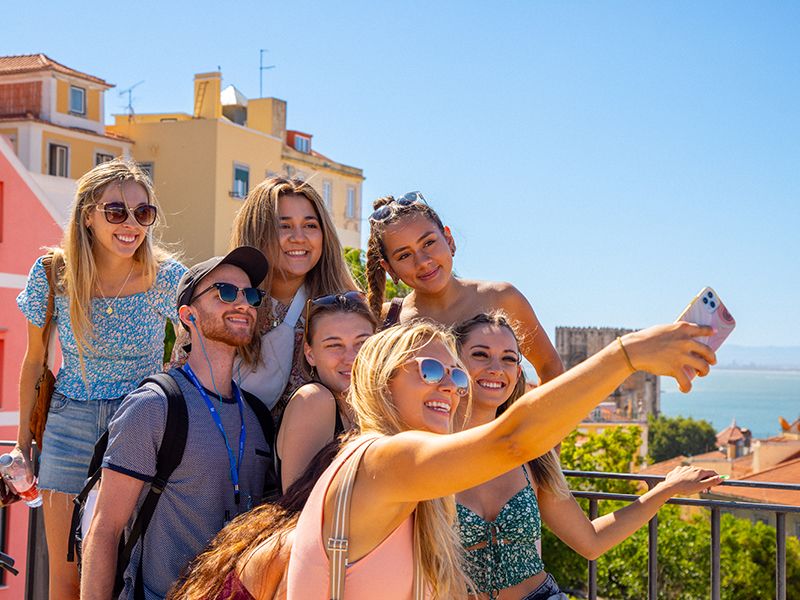 Group of young adults taking a selfie in front of colorful buildings in Lisbon