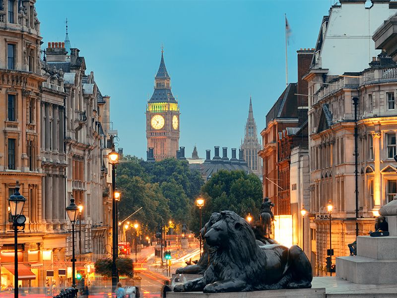 Two bronze lion statues in Trafalgar Square with Big Ben clock tower in the background