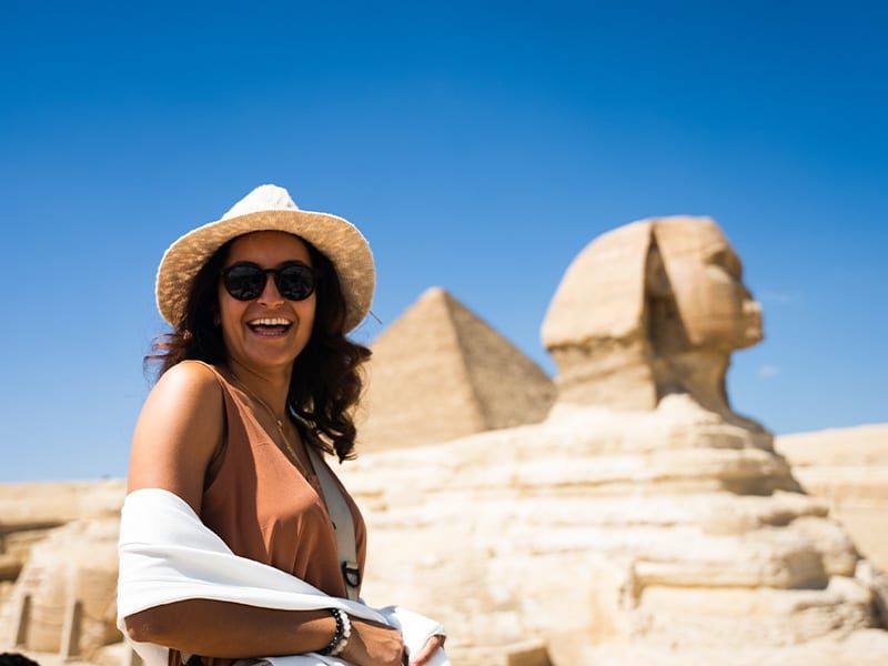 A woman wearing a hat and smiling in front of the Great Sphinx