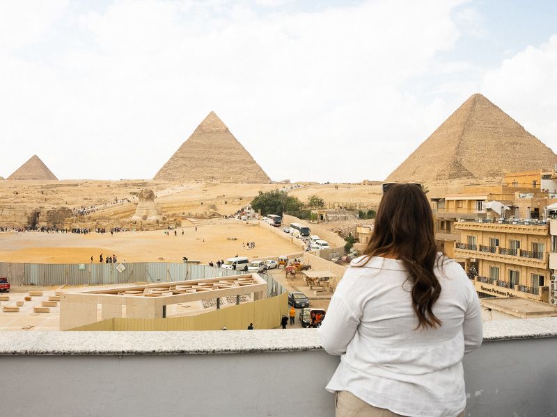 Woman standing on a balcony overlooking the Great Pyramids.