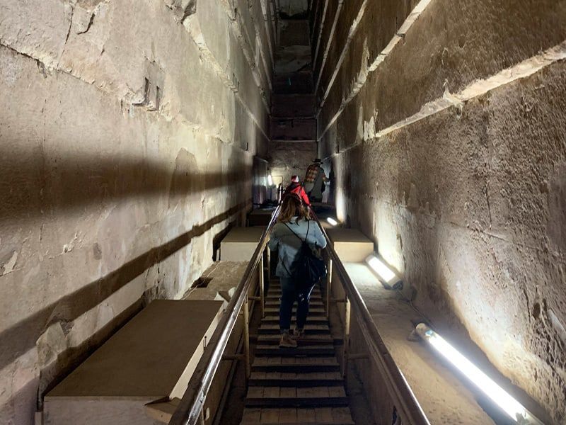 A few people walking up a narrow staircase with stone on either side