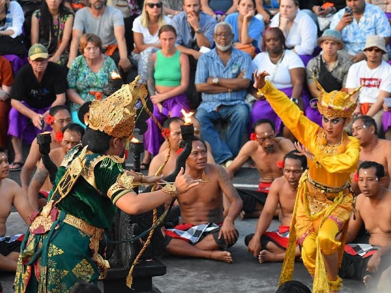 Two people in traditional costume performing for a seated audience. 