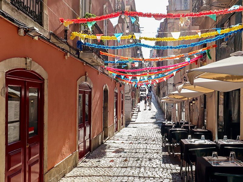 Lisbon alley with outdoor tables and colorful streamers hanging between buildings