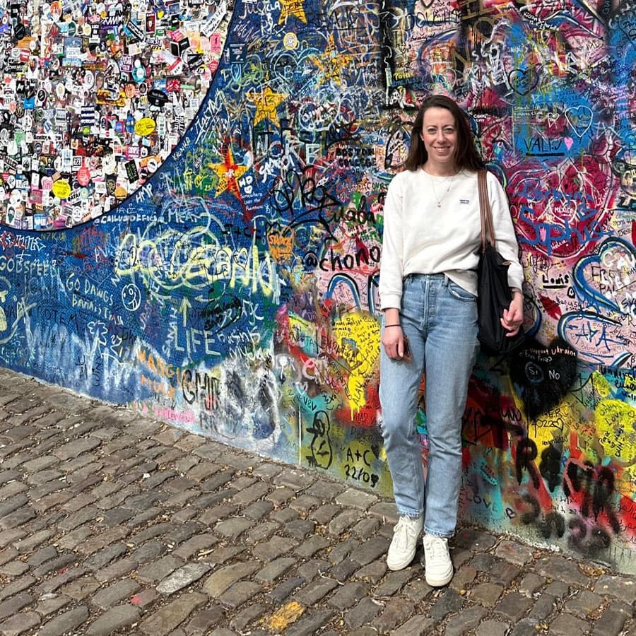 A woman smiling in front of a painted wall.