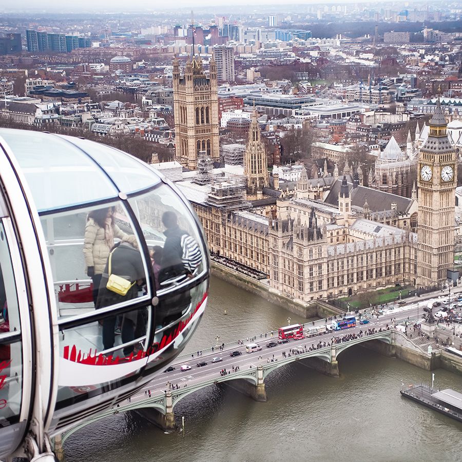 Several people inside a capsule of the London Eye with the House of Parliament in the background