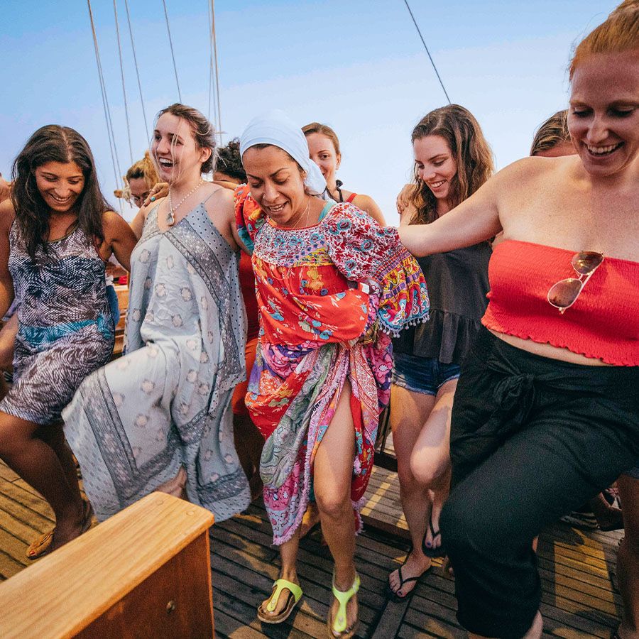 Several women standing side by side smiling and dancing