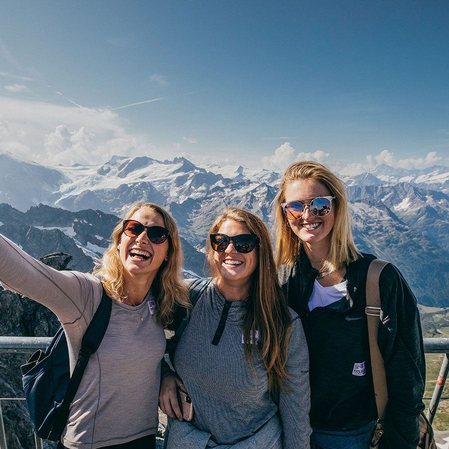 Three women smiling for a selfie with mountains in the background.