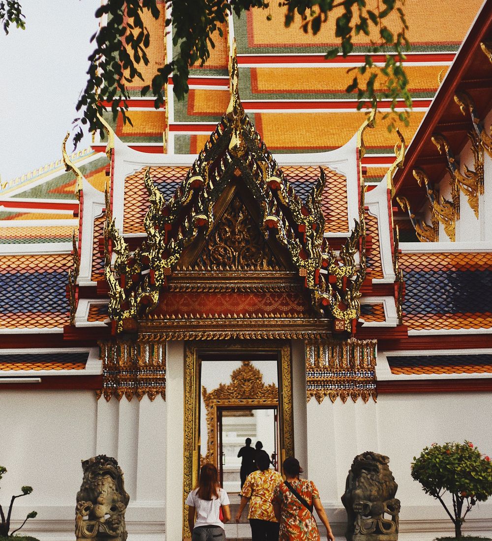 three people stepping into the entrance of wat pho temple in bangkok thailand