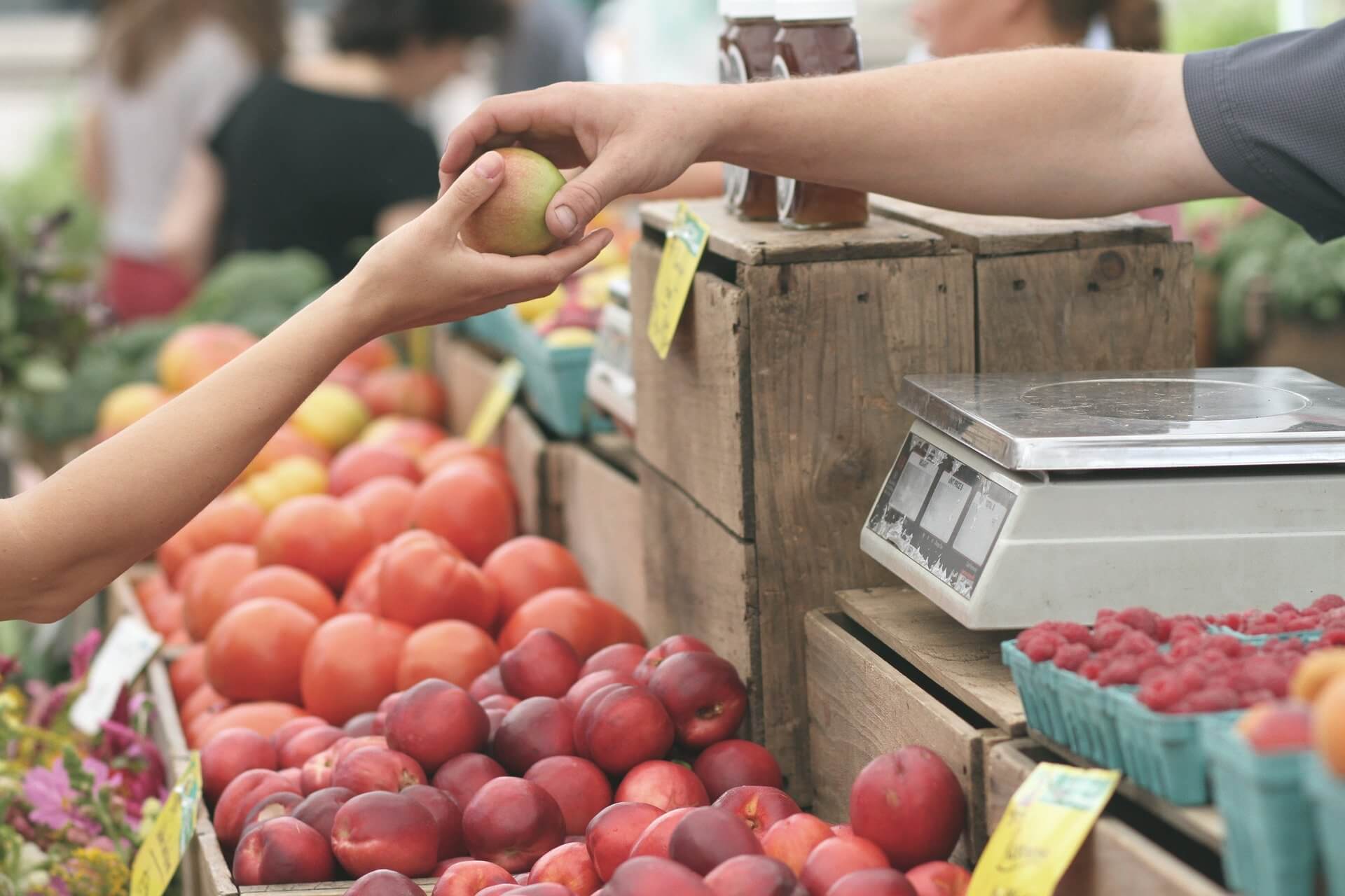 groenteboer op de markt geeft appel aan klant