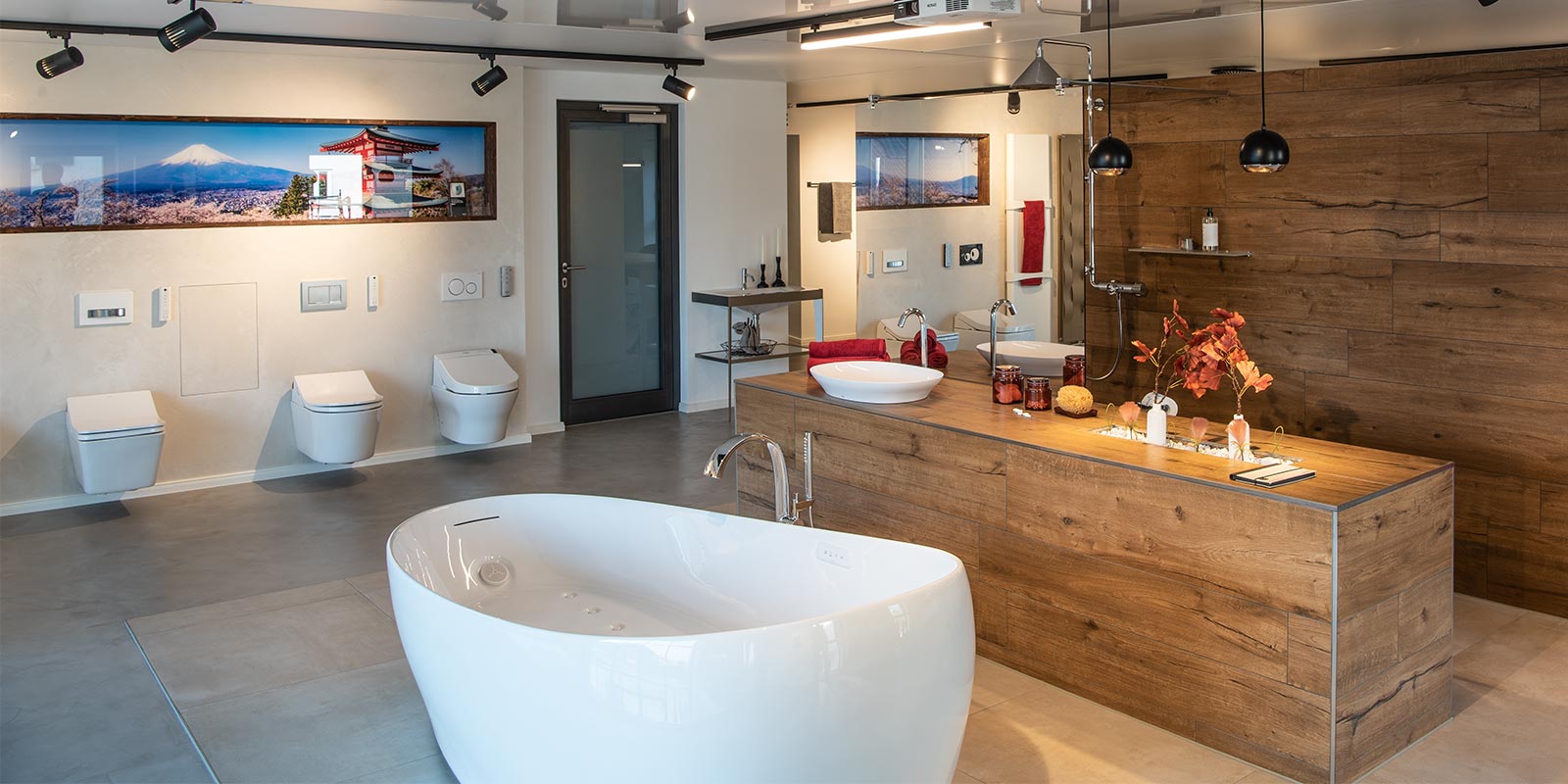 Filiale eines Badgestalters. Badewanner im Vordergrund, Holztheke mit Pendelleuchten von SLV im Hintergrund. Spotlights an Schiene.