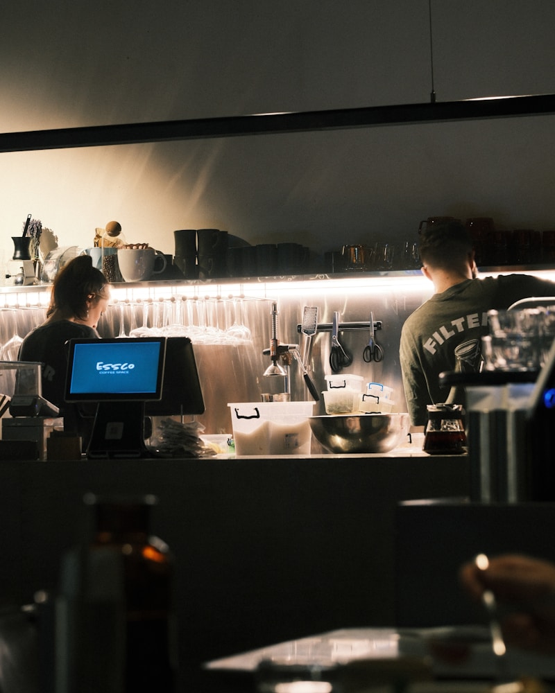 Baristas preparing coffee behind a busy cafe counter during a shift