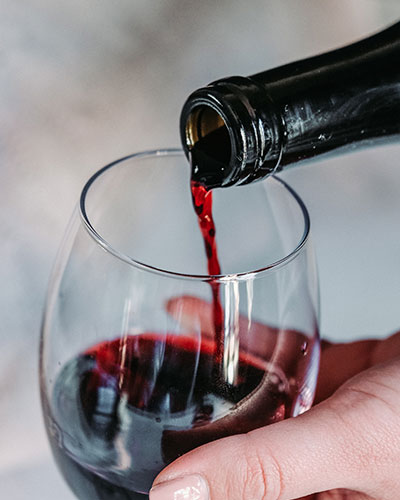 Rotwein wird in ein Weinglas geschüttet