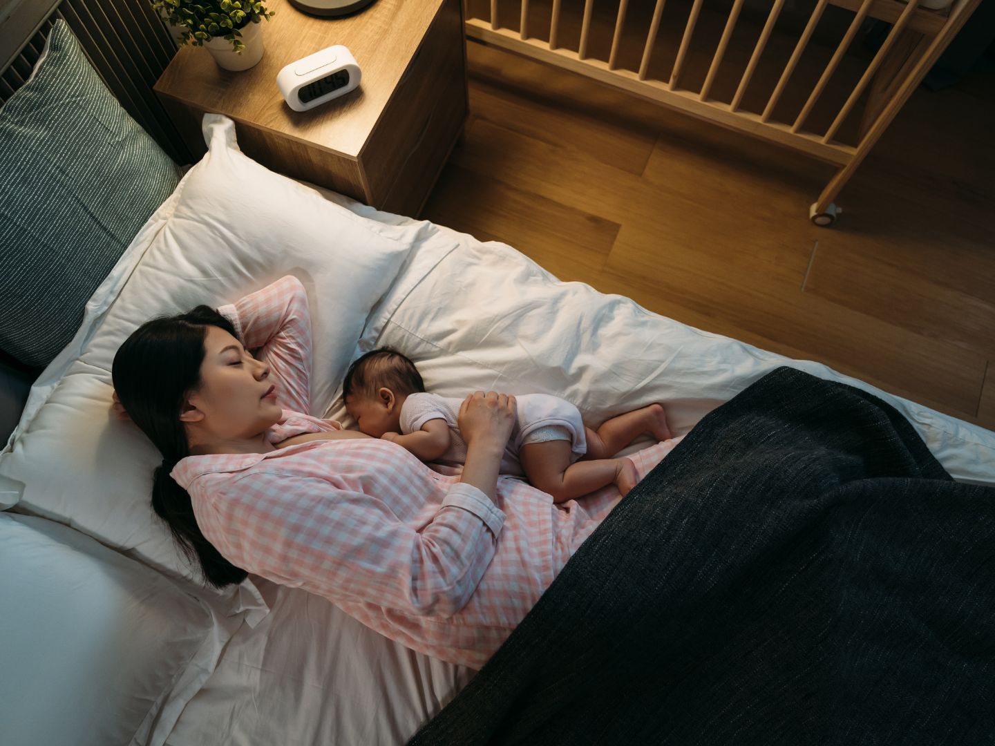 asian mom wearing pajama sleeping while breastfeeding newborn